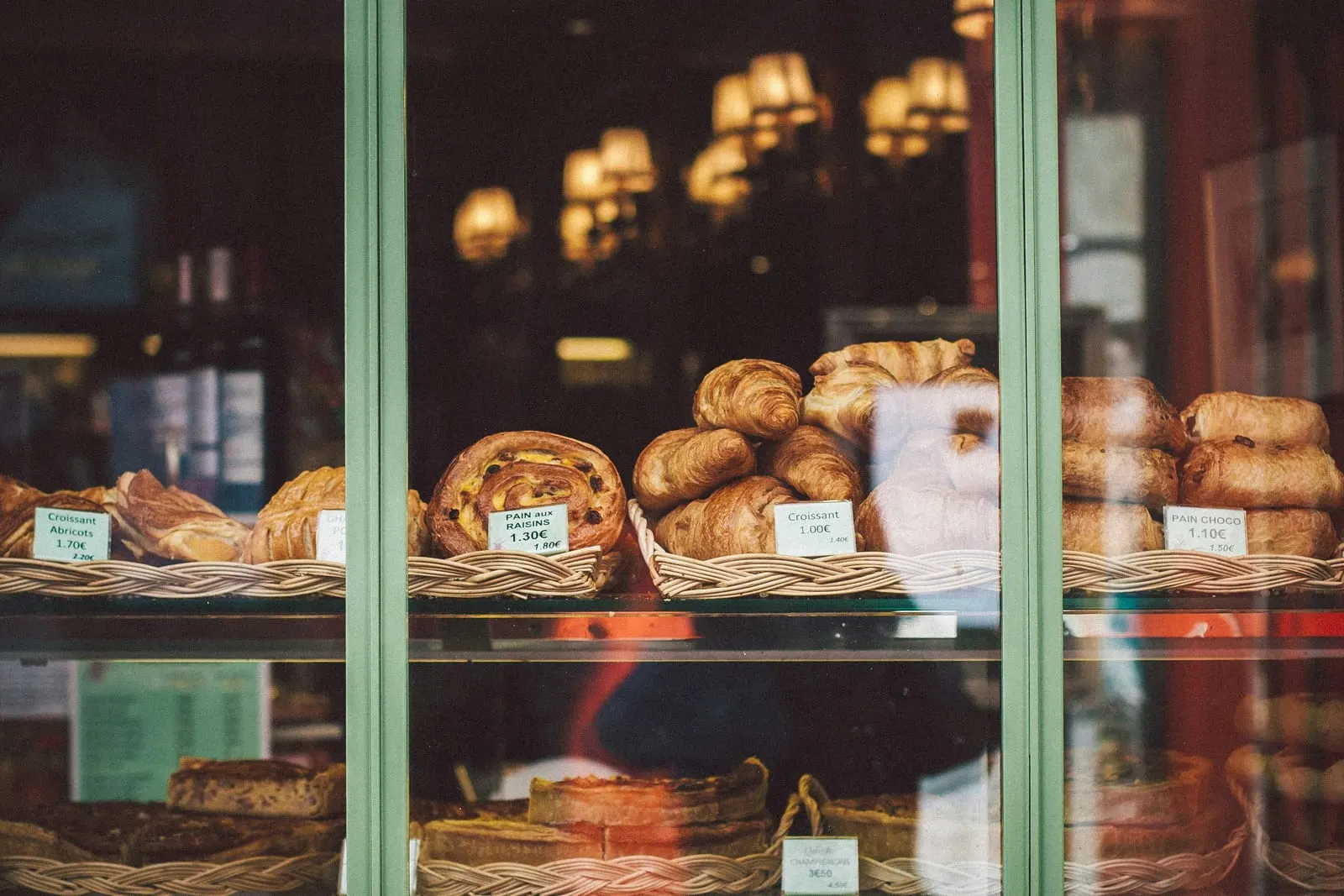 Croissants and pastries lit warmly in a bakery window