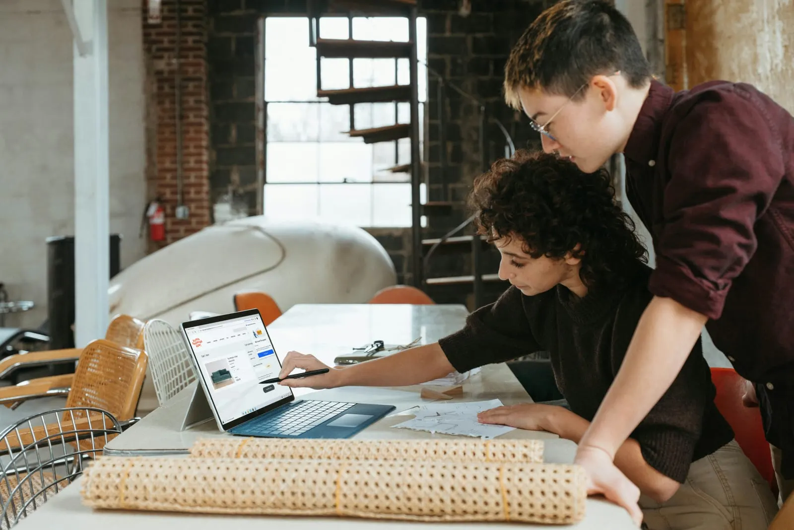 Two makers looking over their work at a laptop in a warm workshop